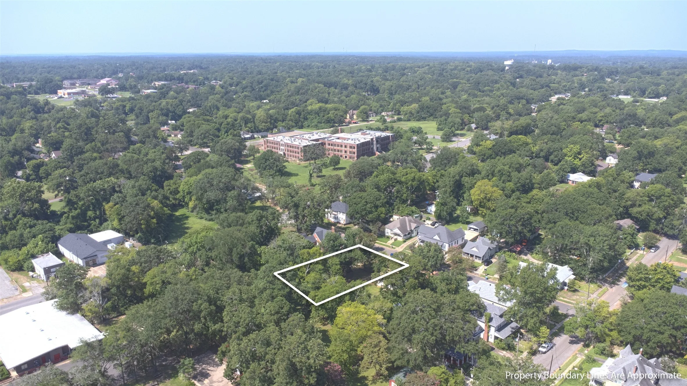 Land parcel with mature trees, surrounded by established residential properties and distant institutional buildings