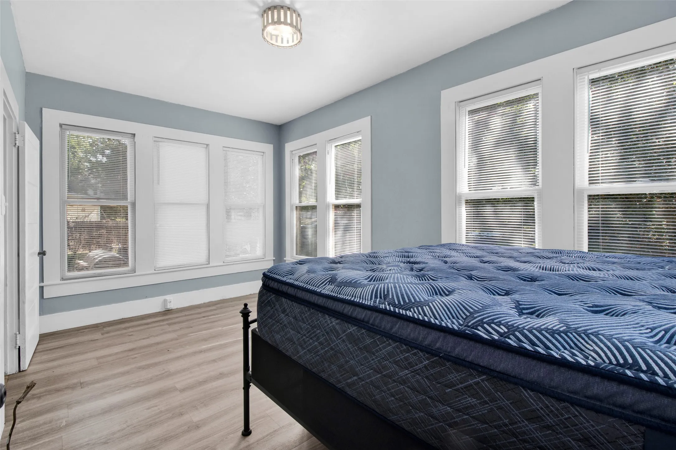 Bright room featuring multiple windows, wood-finish flooring, and a modern flush-mount light fixture