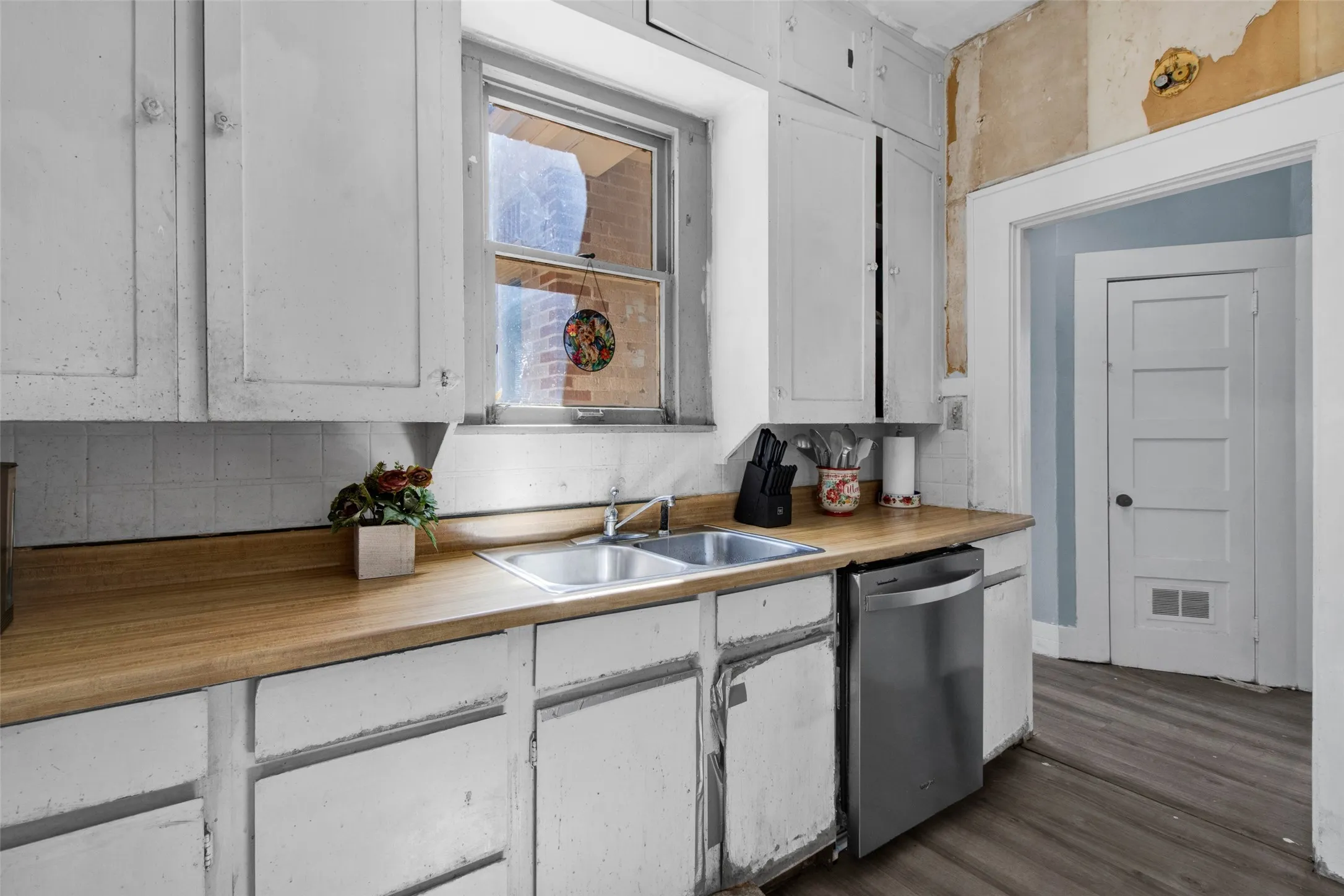 Kitchen area featuring a stainless steel dishwasher, double basin sink, and wood-finish countertops