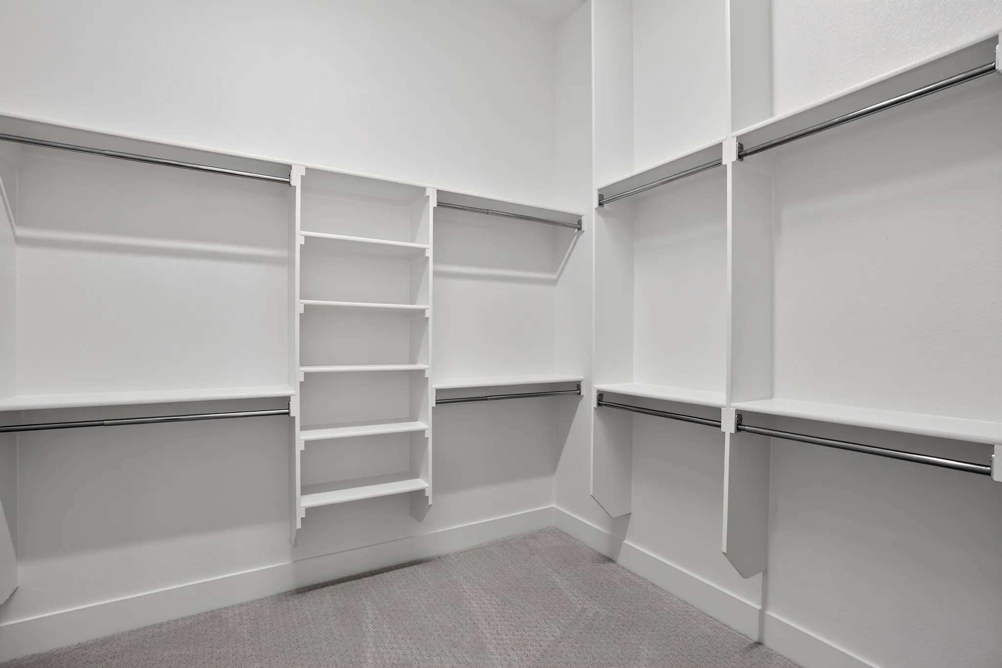 Built-in closet system featuring multiple hanging rods, ample shelving, and textured carpeting