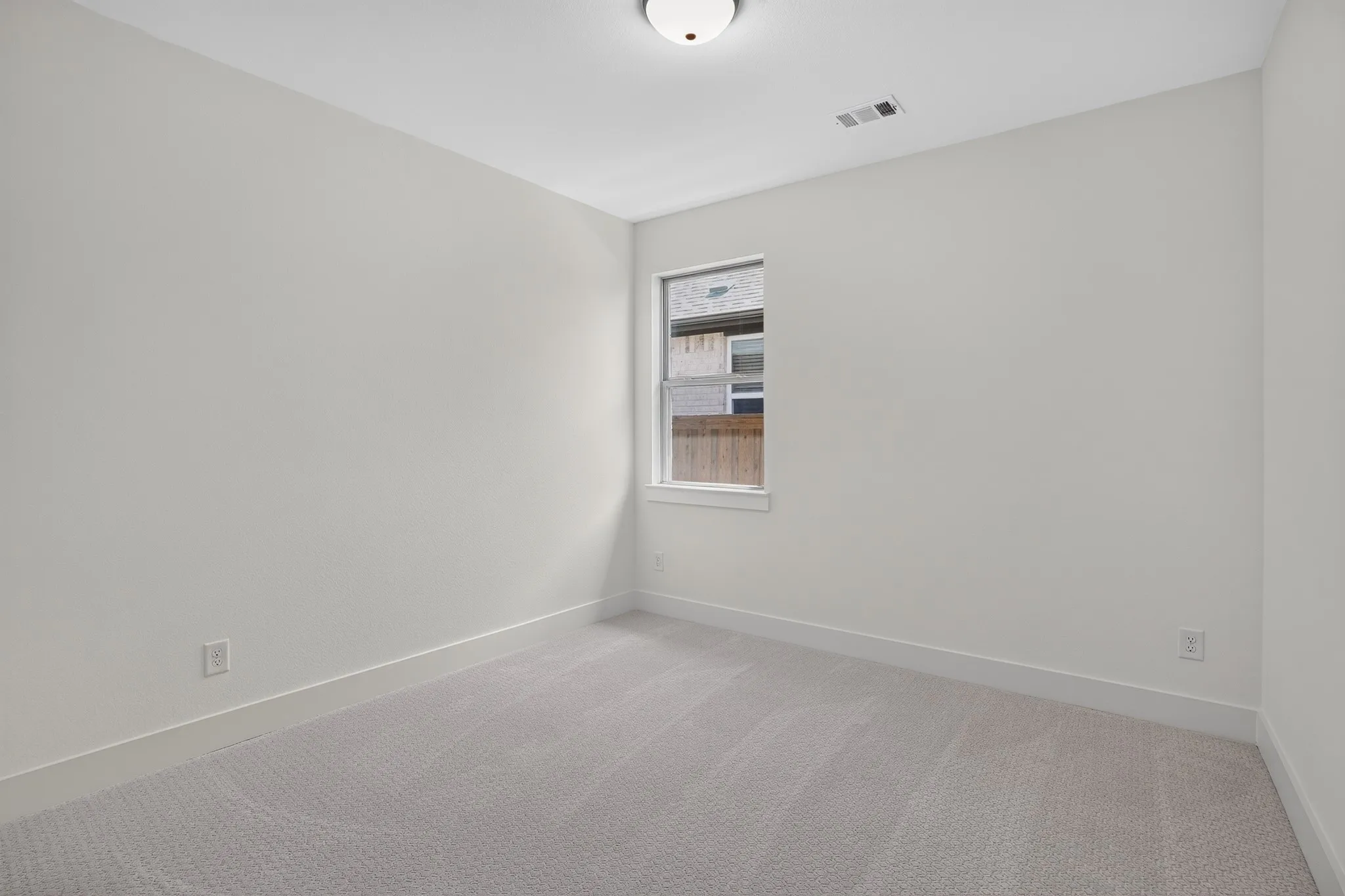 Bright secondary bedroom with neutral wall finishes, recessed ceiling lighting, and carpet flooring
