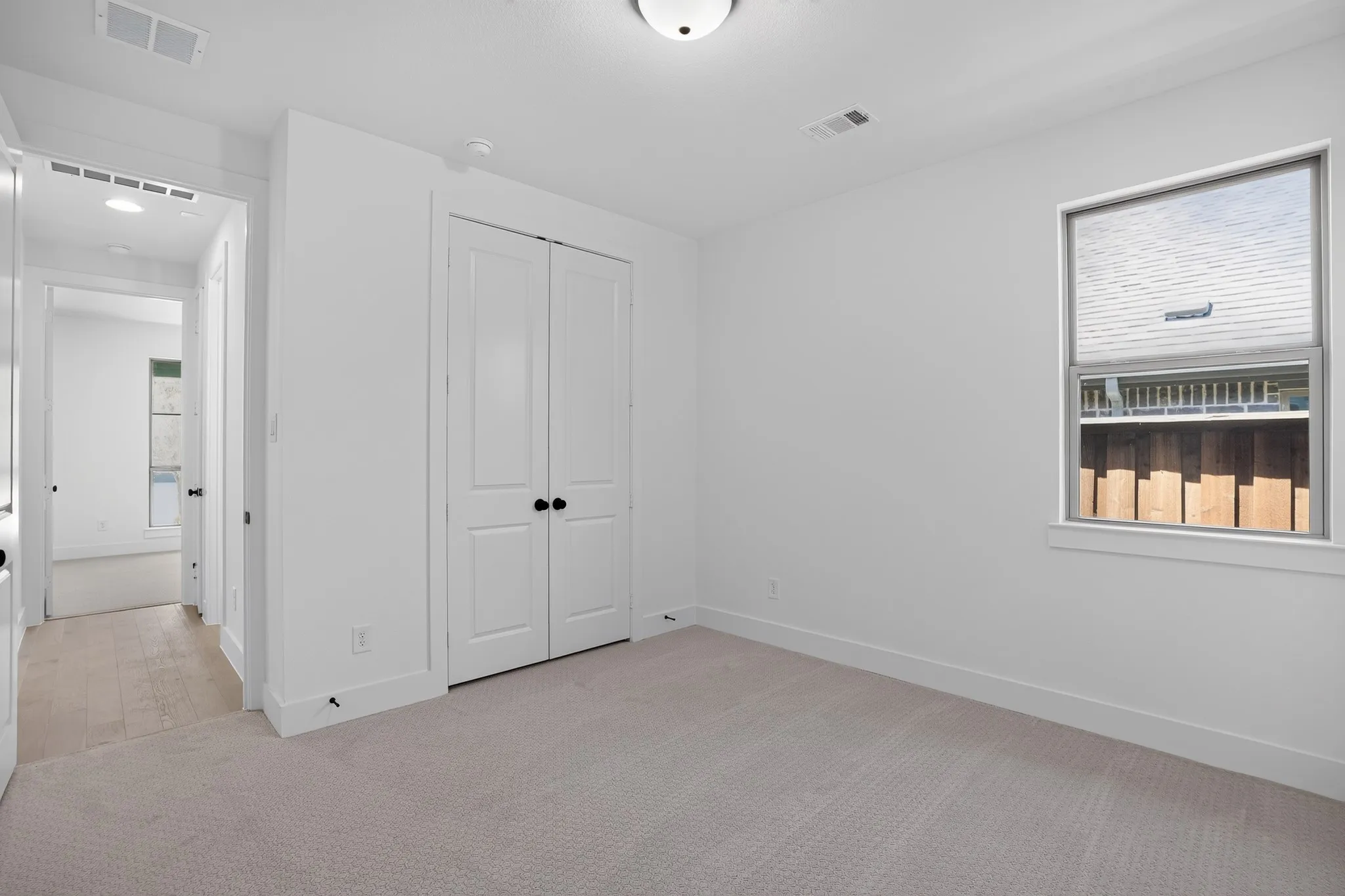 Carpeted flooring, white walls, double-door closet, single window with blinds, and flush mount ceiling light