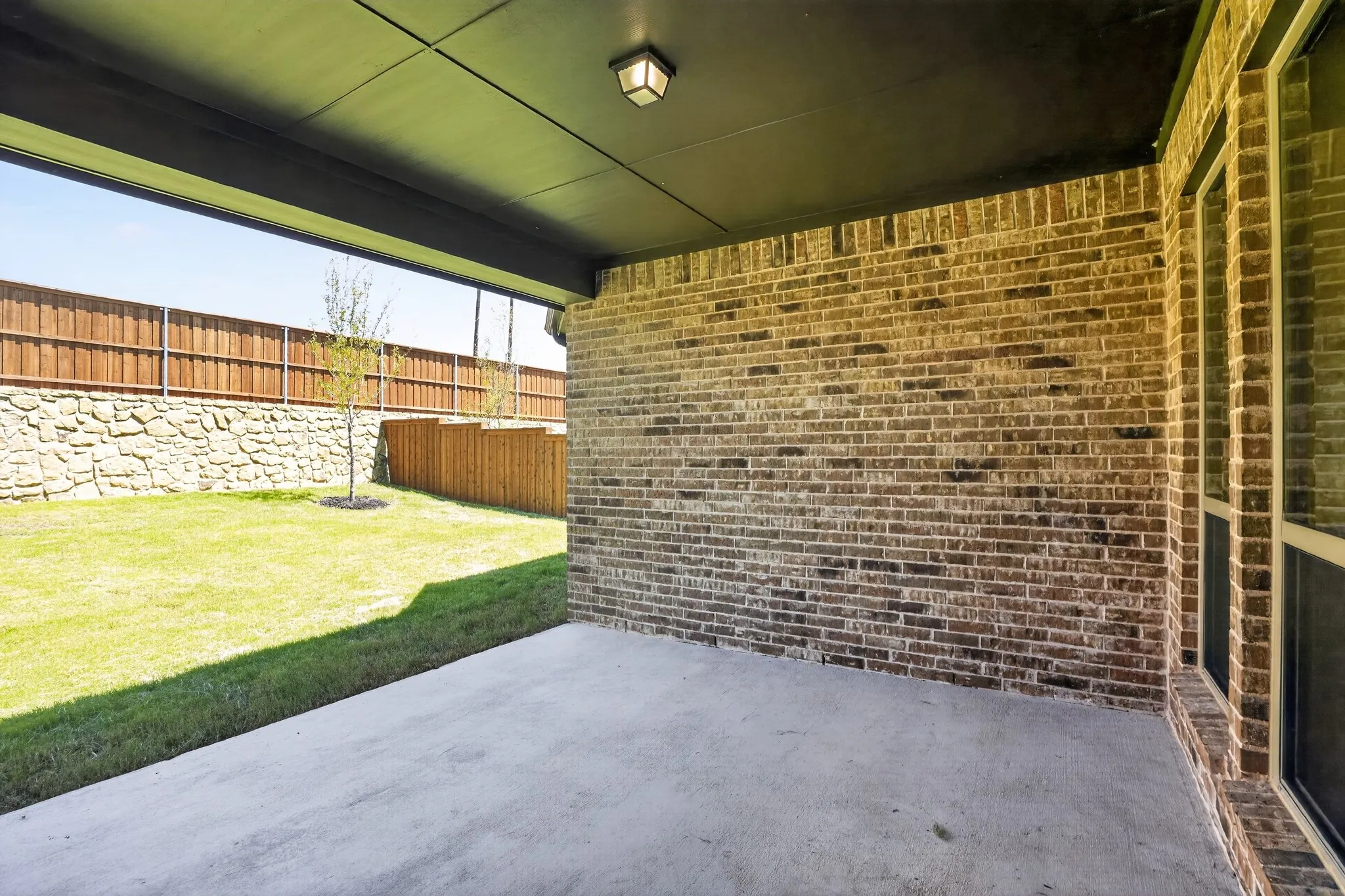 Covered patio with a concrete surface, a brick exterior wall, and a recessed ceiling light
