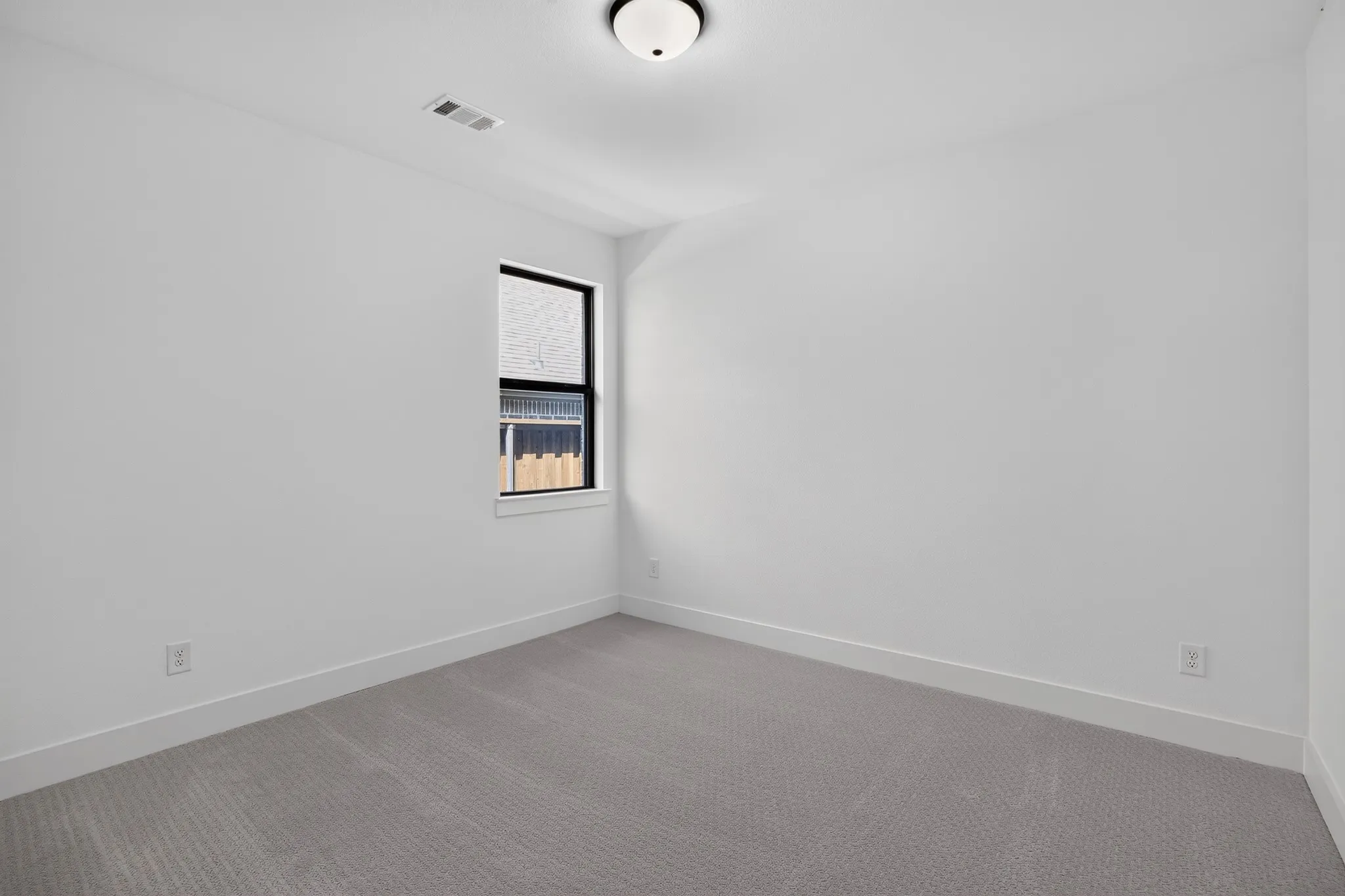 Neutral wall color, carpeted flooring, and a single window with dark trim