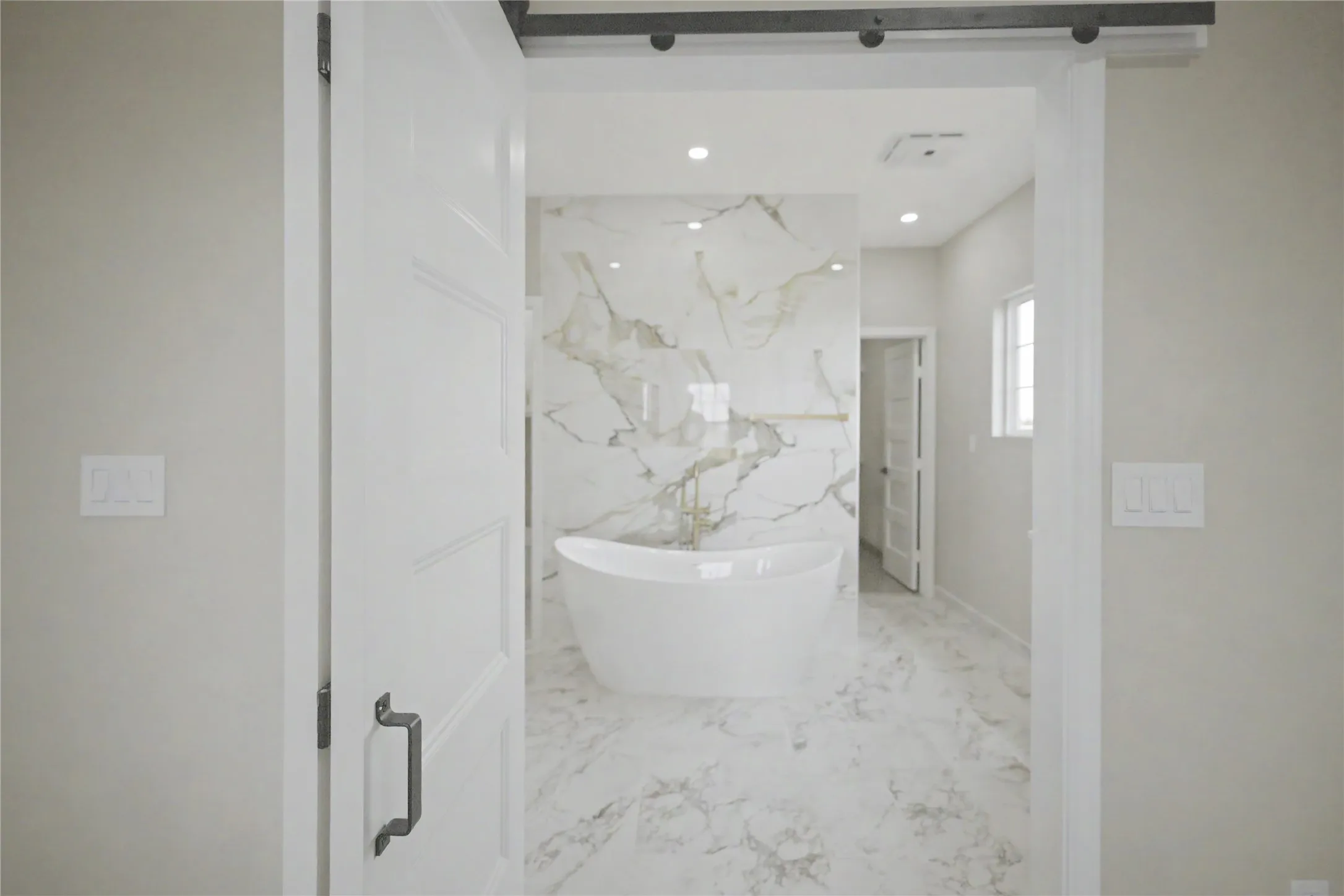 Bathroom featuring a freestanding soaking tub, large-format marbled tile flooring, and a coordinating marbled accent wall