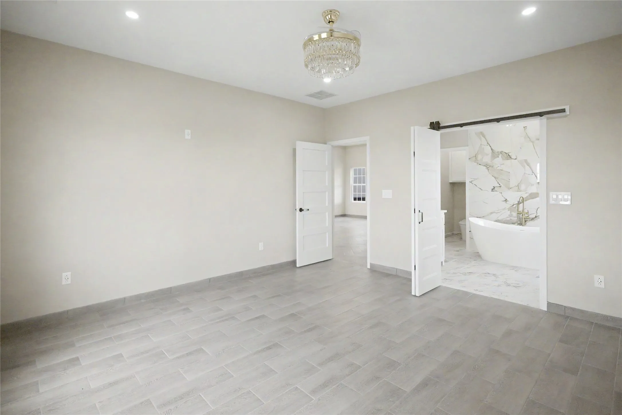 Spacious room featuring light-toned walls and wood-look tile flooring