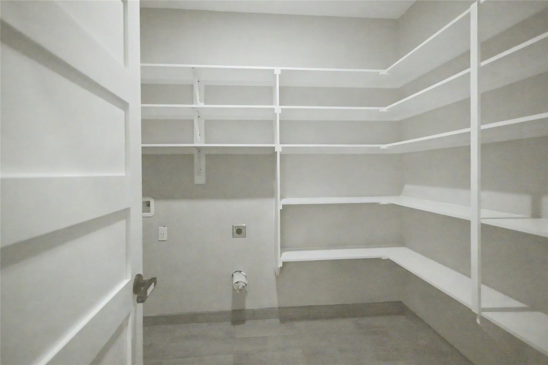 Utility room featuring extensive built-in shelving, durable flooring, and a panel door with dark hardware