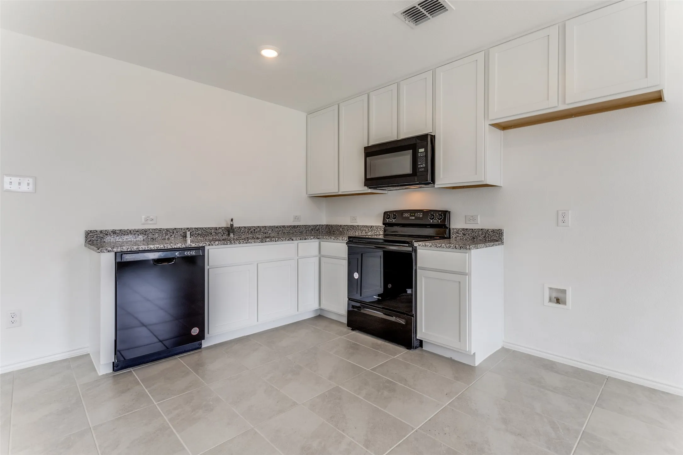 Kitchen featuring white cabinets, black appliances, light tile floors, and light stone​​‌​​​​‌​​‌‌​‌‌​​​‌‌​‌​‌​‌​​​‌​​ counters
