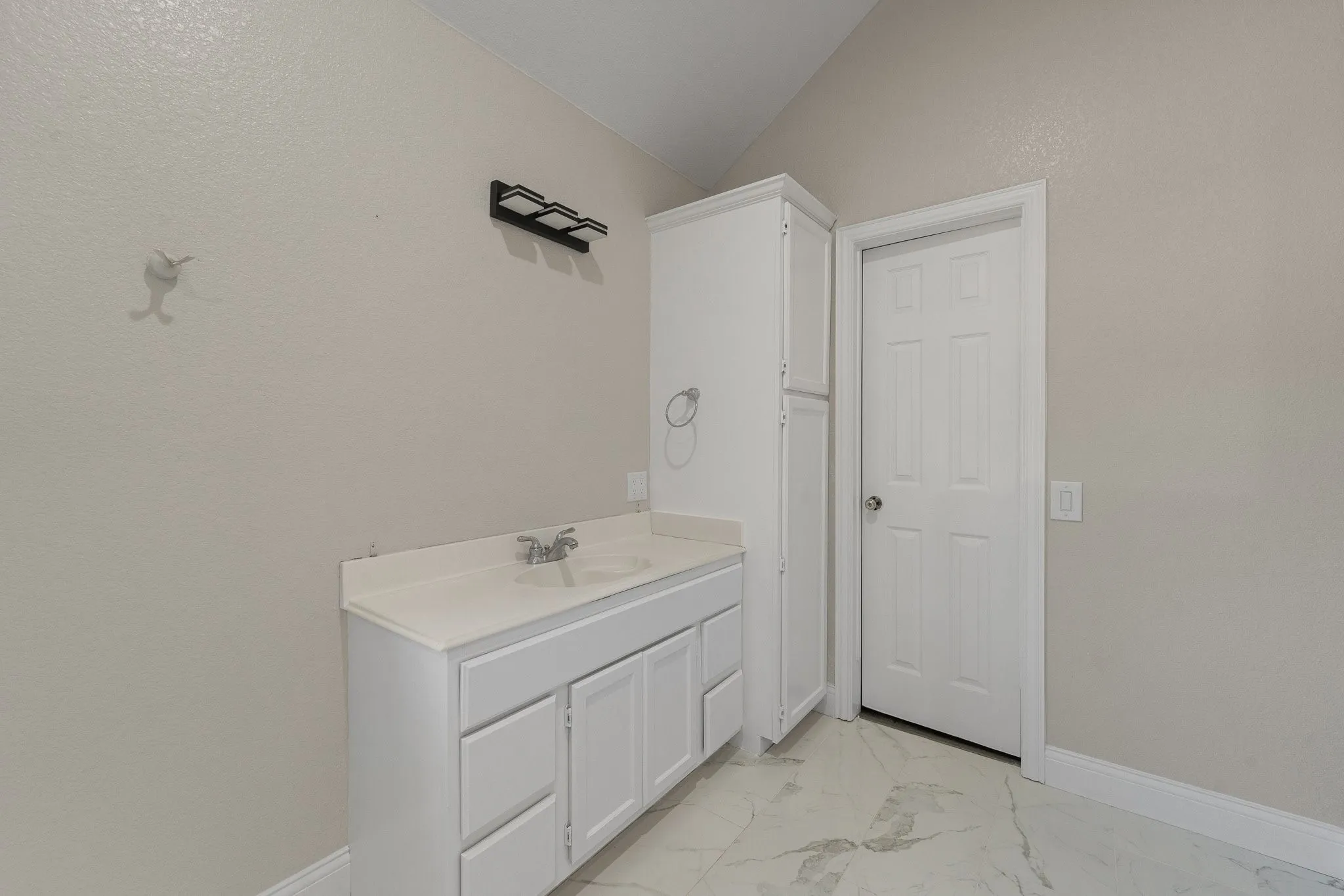 Bathroom featuring a white vanity with integrated sink, white cabinetry, and white paneled door