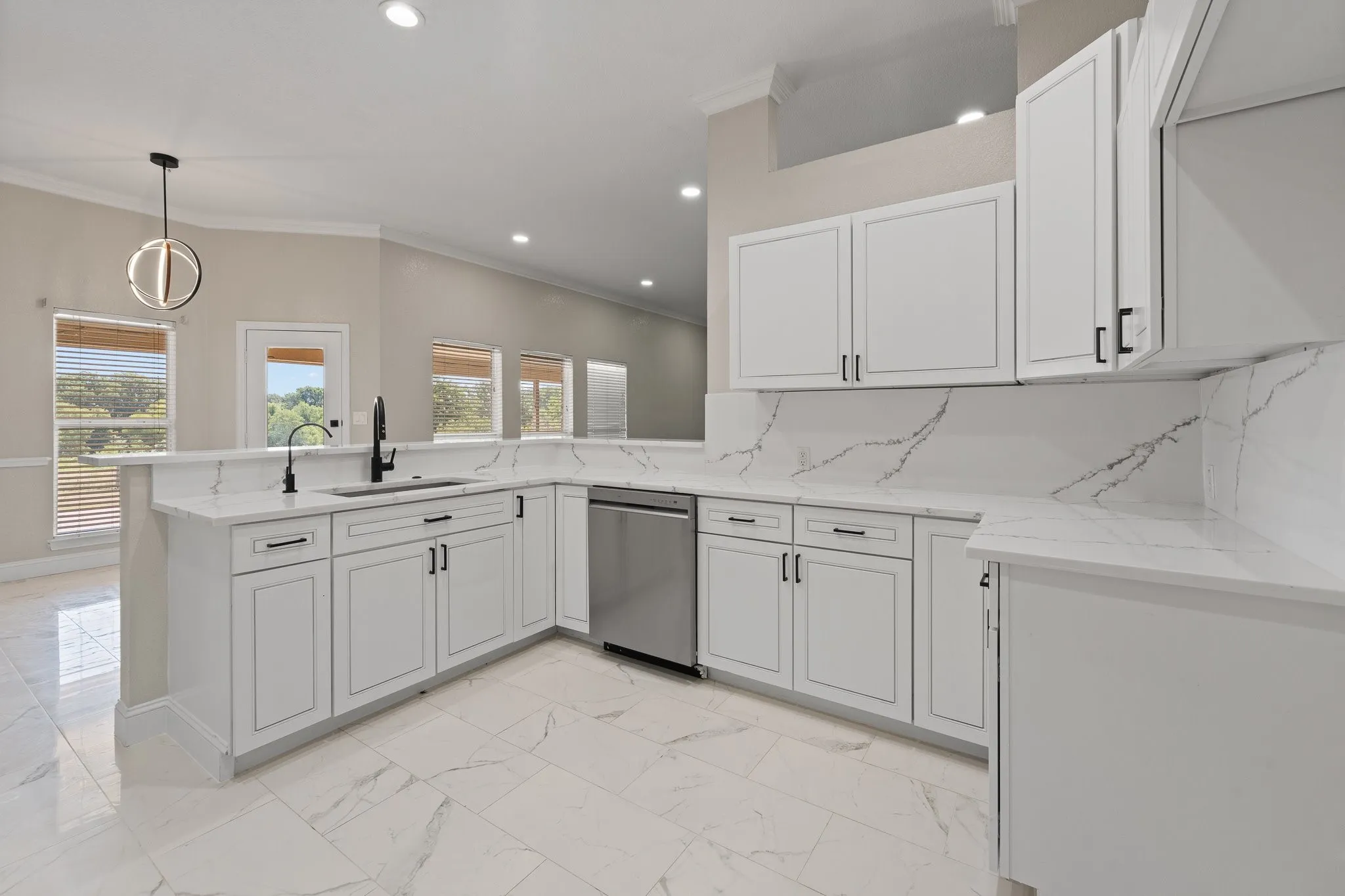Kitchen featuring white cabinetry with black hardware, white countertops with natural veining, and a stainless steel dishwasher