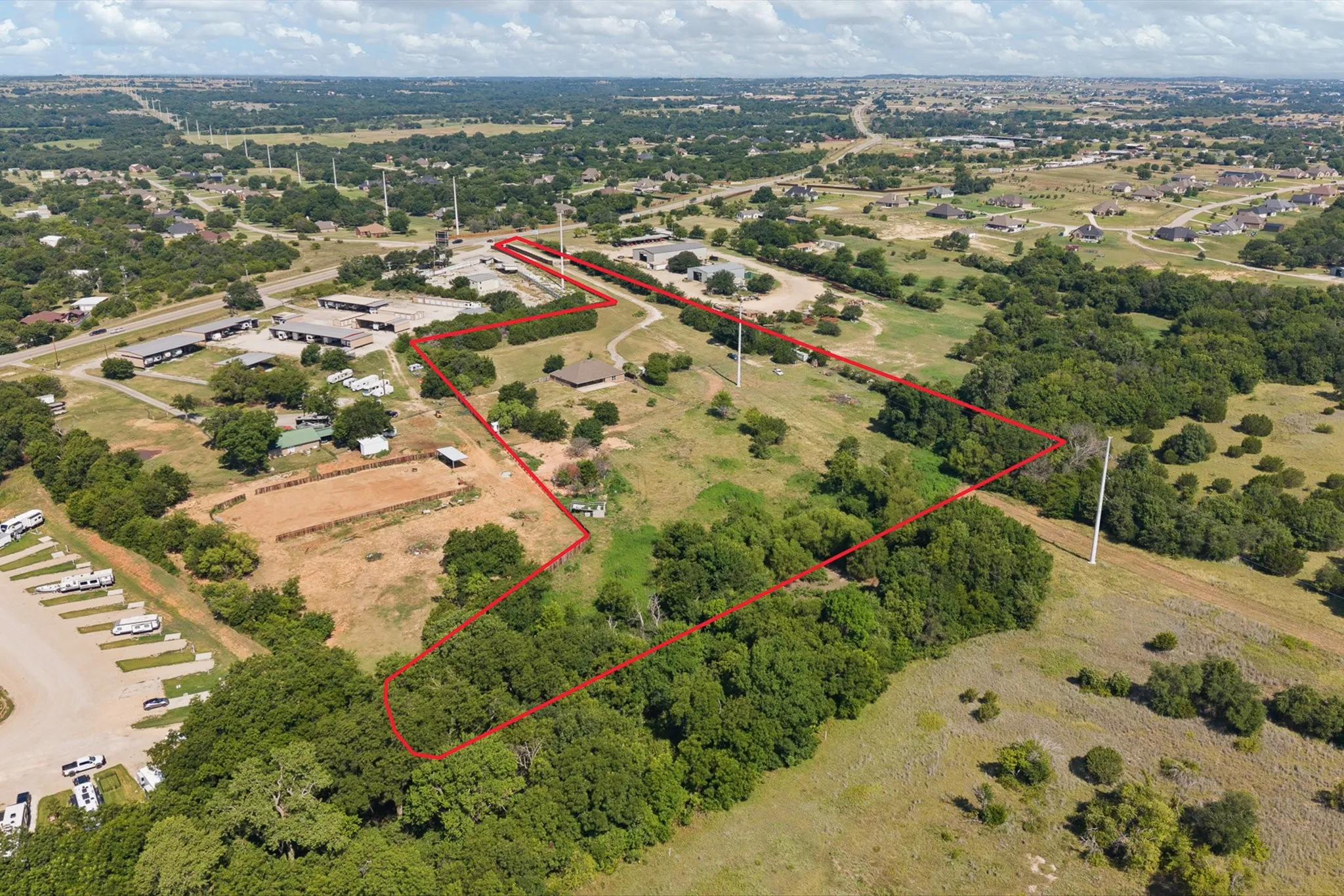 Expansive land parcel featuring a defined boundary, a mix of cleared areas, and mature tree coverage