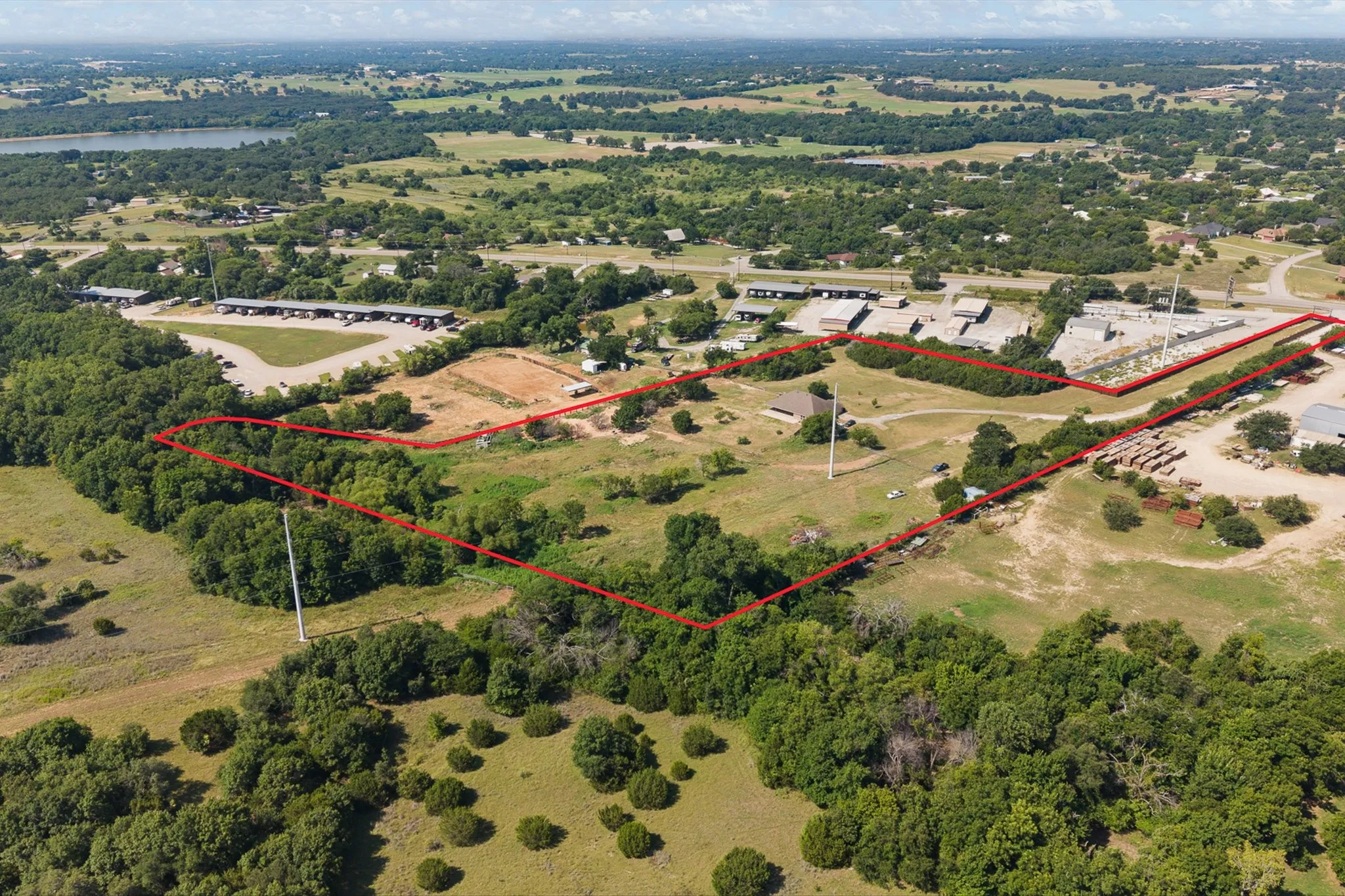 Expansive land parcel featuring varied terrain, mature tree coverage, clearings, and existing structures