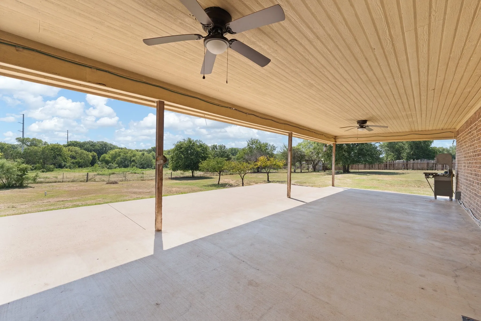 Expansive covered patio featuring a concrete surface and a wood-paneled ceiling