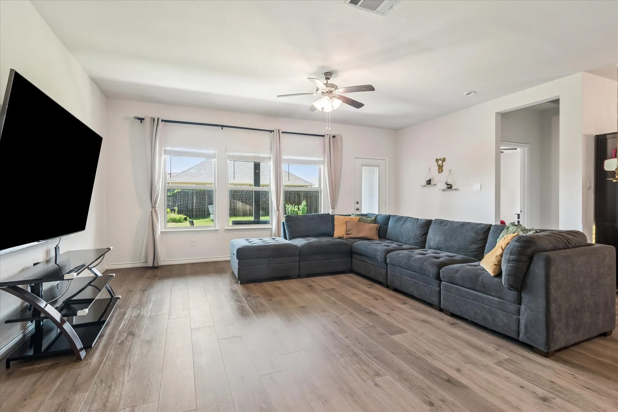 Open-concept living area featuring wood-finish flooring, recessed lighting, and a ceiling fan with light kit