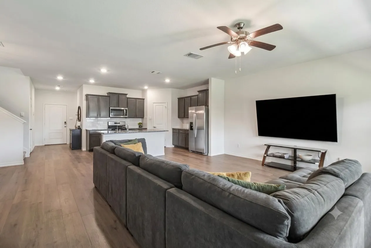 Open-concept living area featuring wood-finish flooring, recessed lighting, and a ceiling fan with light kit