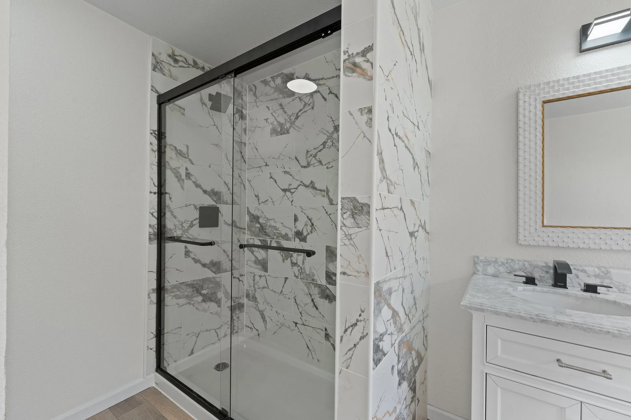 Shower enclosure with black-framed glass doors and white veined tile surround