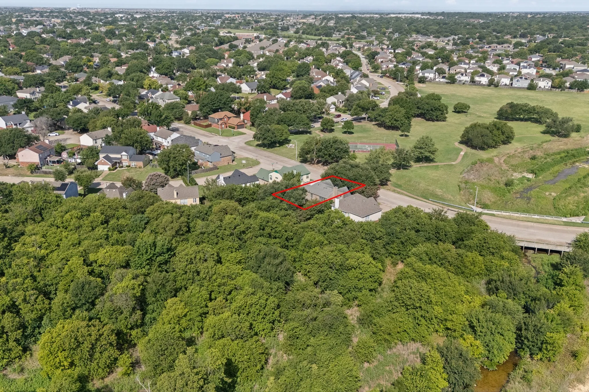 Aerial perspective showcasing a residential property nestled within a lush, treed landscape