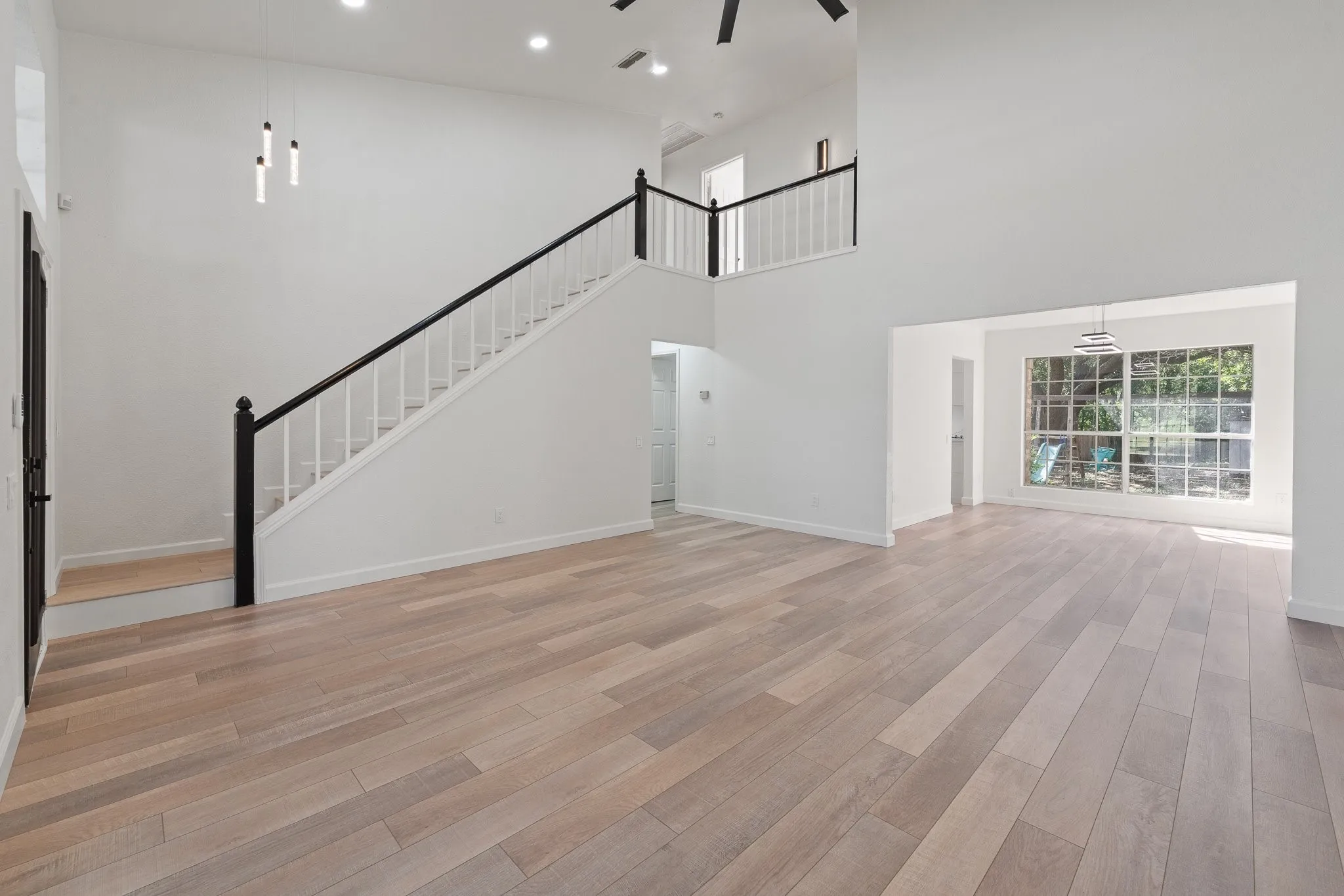 Expansive living area featuring light wood-finish flooring and a two-story ceiling