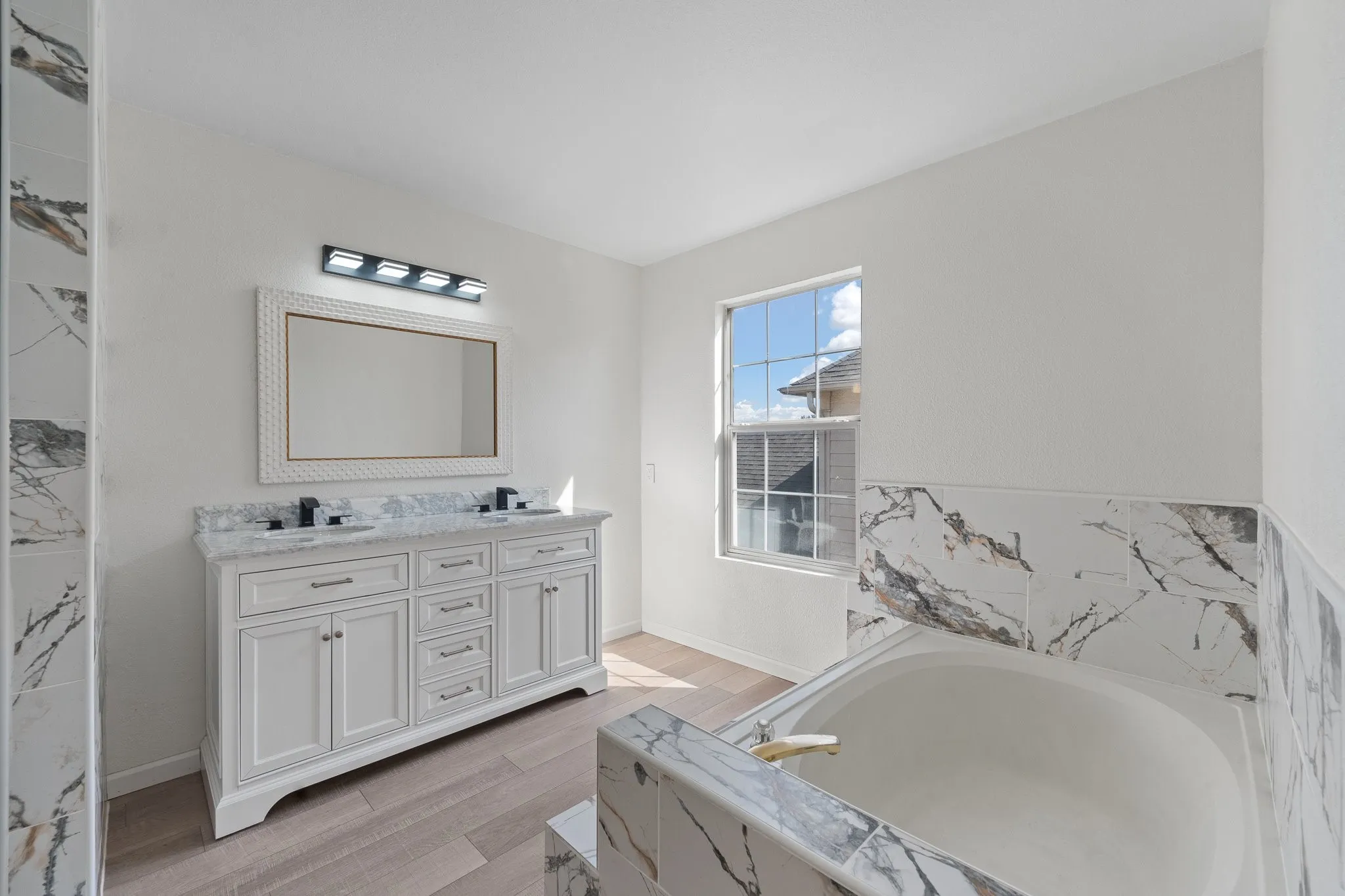 Bathroom featuring a double vanity with stone countertop, dual undermount sinks, and matte black fixtures
