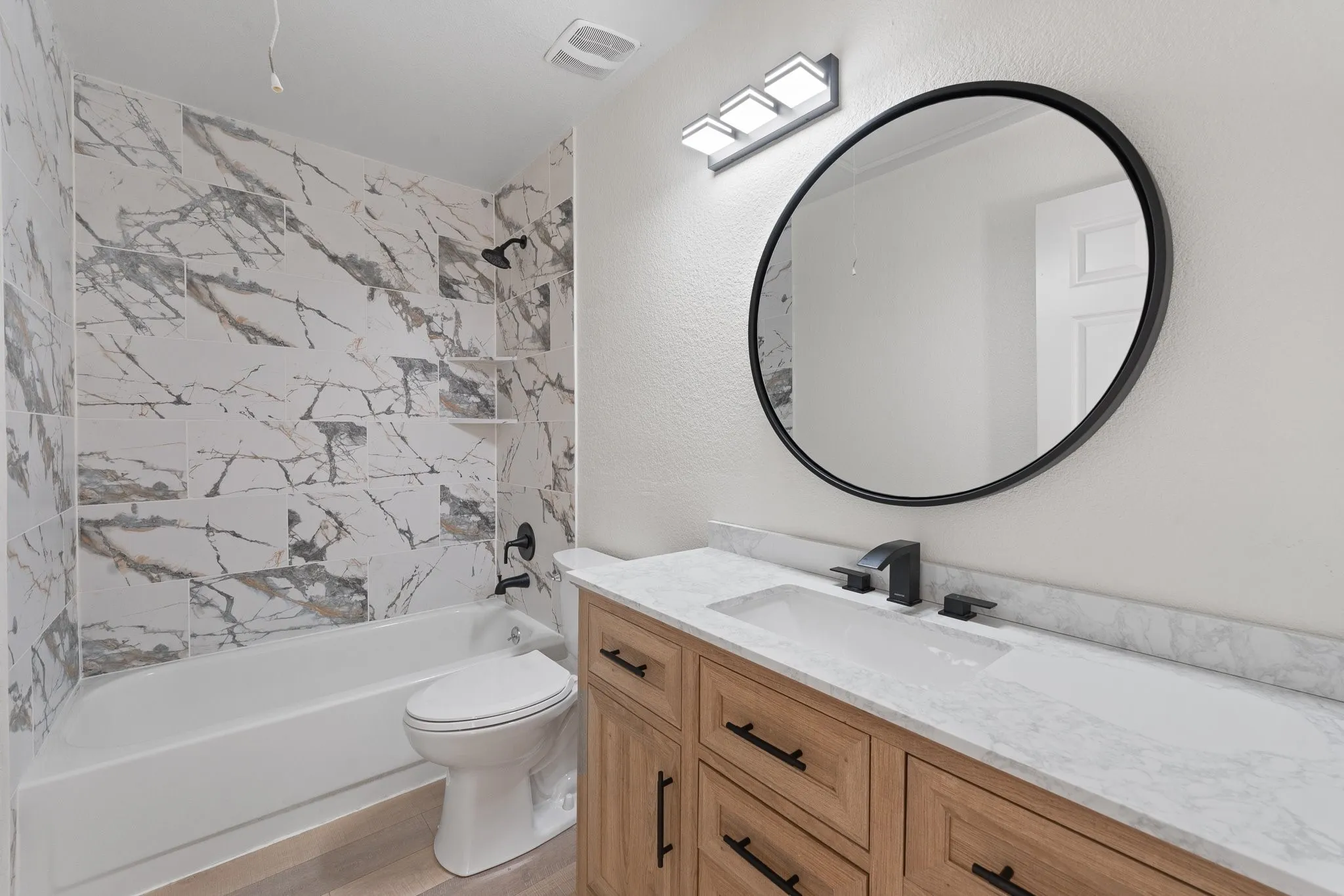 Bathroom featuring a wood-finish vanity with an integrated white sink and a light-toned countertop