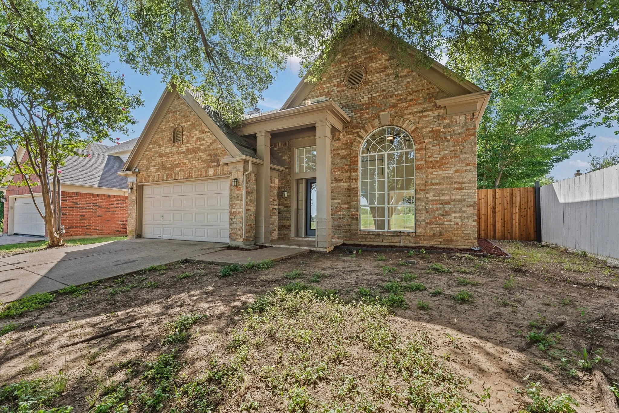 Brick exterior with an arched window, covered entryway, and an attached two-car garage