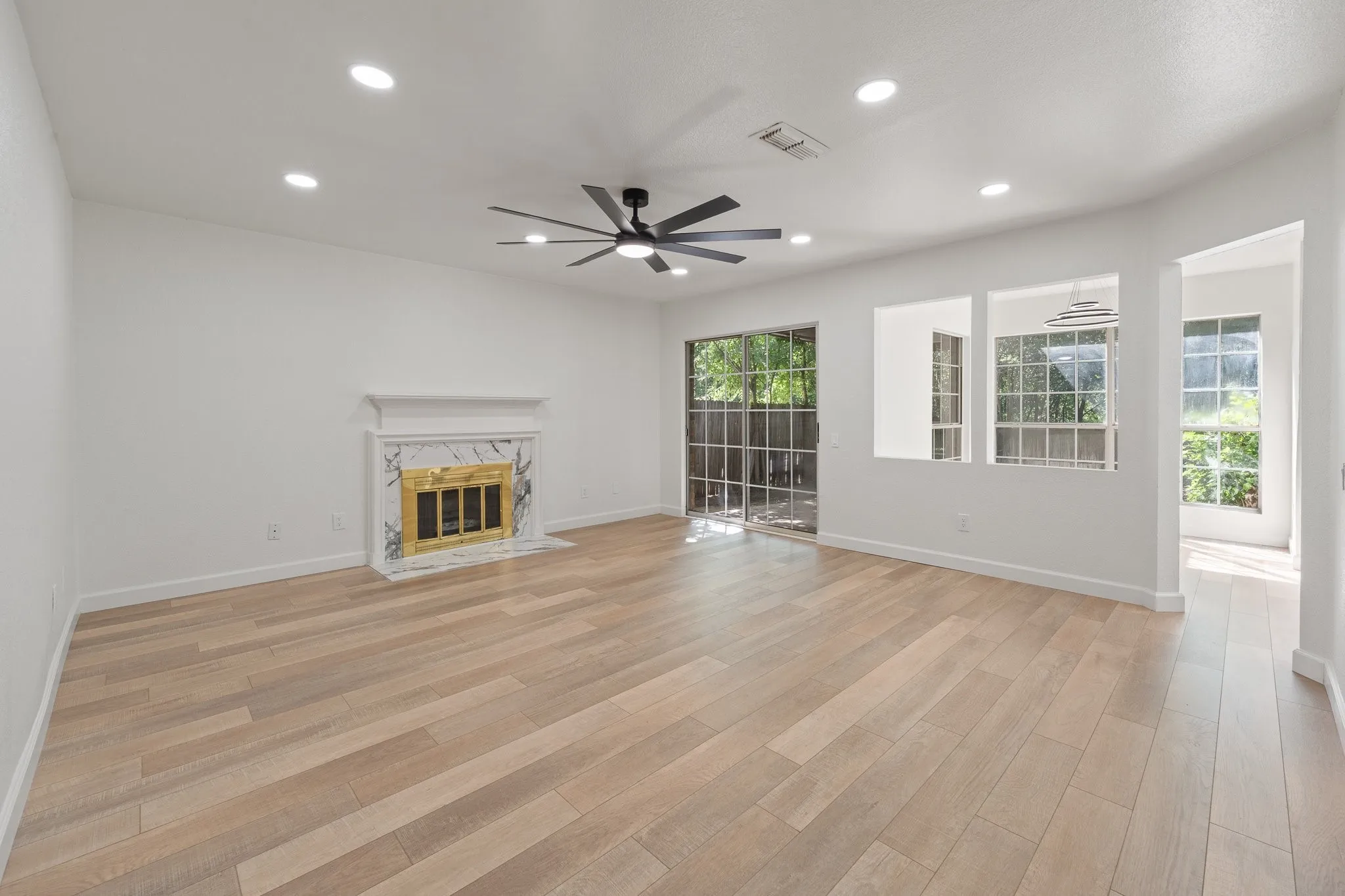 Expansive living area featuring wood-finish flooring, a contemporary ceiling fan, and recessed lighting