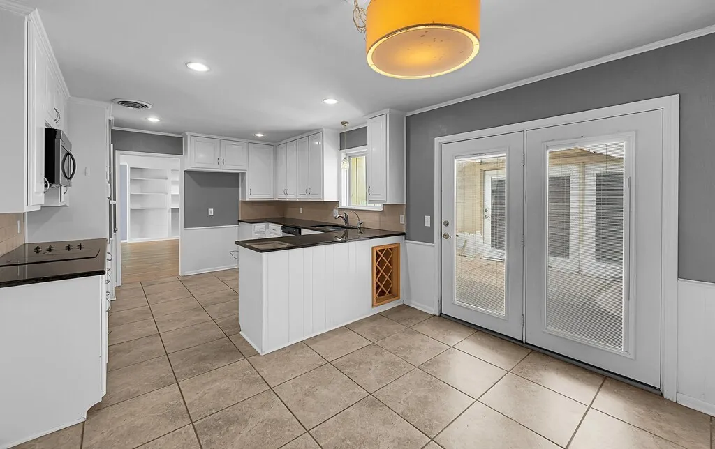 Kitchen featuring white cabinetry, dark countertops, a built-in microwave, a built-in wine rack, and tile flooring