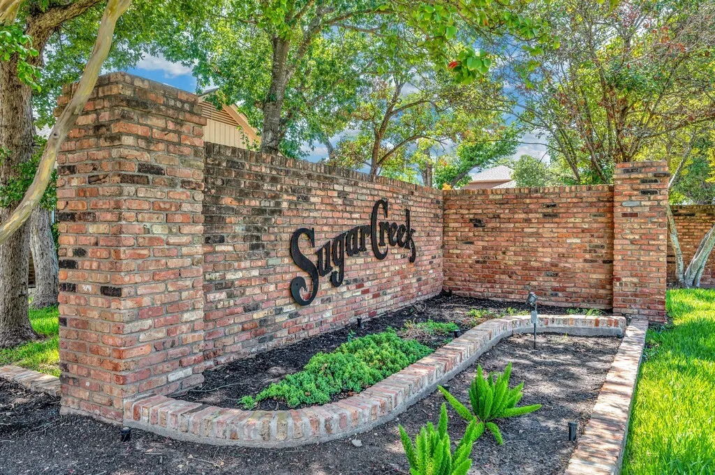 Brick entrance monument with raised garden beds and mature trees