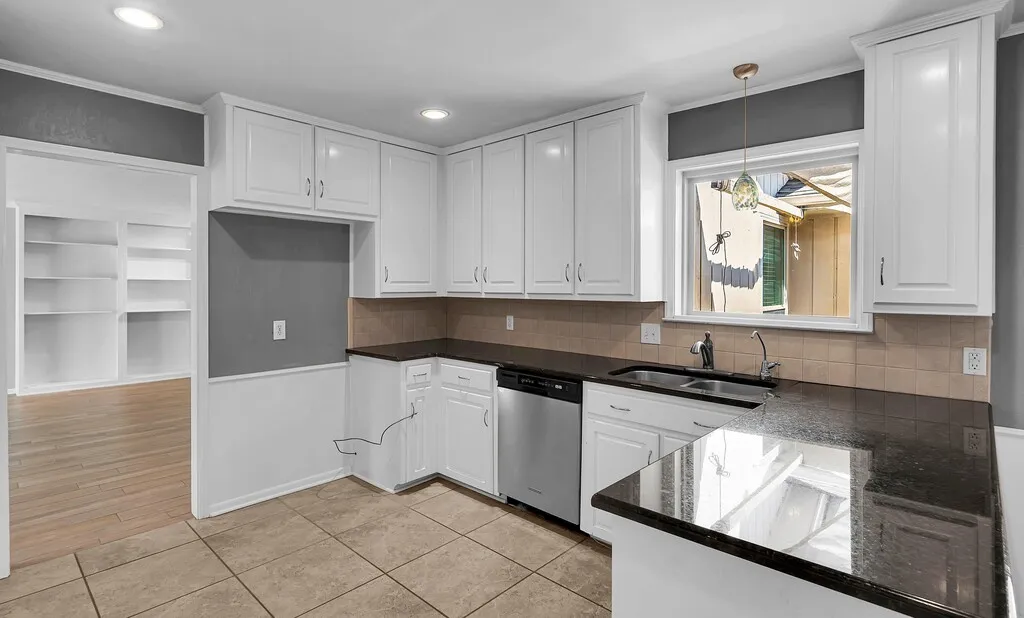 Kitchen featuring white cabinetry, dark countertops, a tile backsplash, and stainless steel appliances