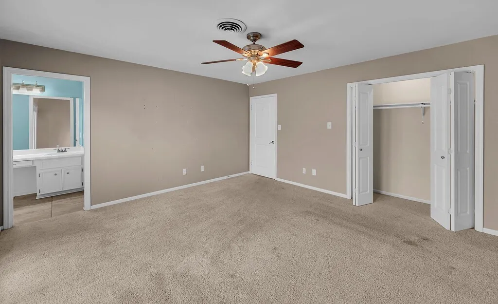 Carpeted bedroom featuring a ceiling fan with light fixture, neutral wall paint, and white trim