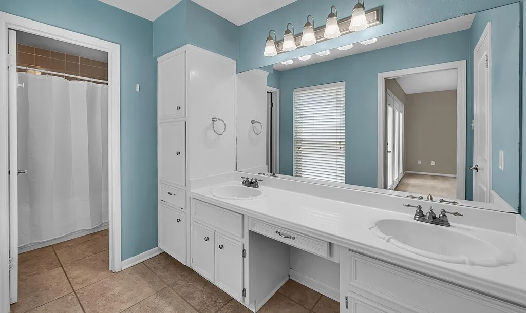 Dual vanity with white cabinetry, integrated sinks, a dedicated makeup area, and tile flooring