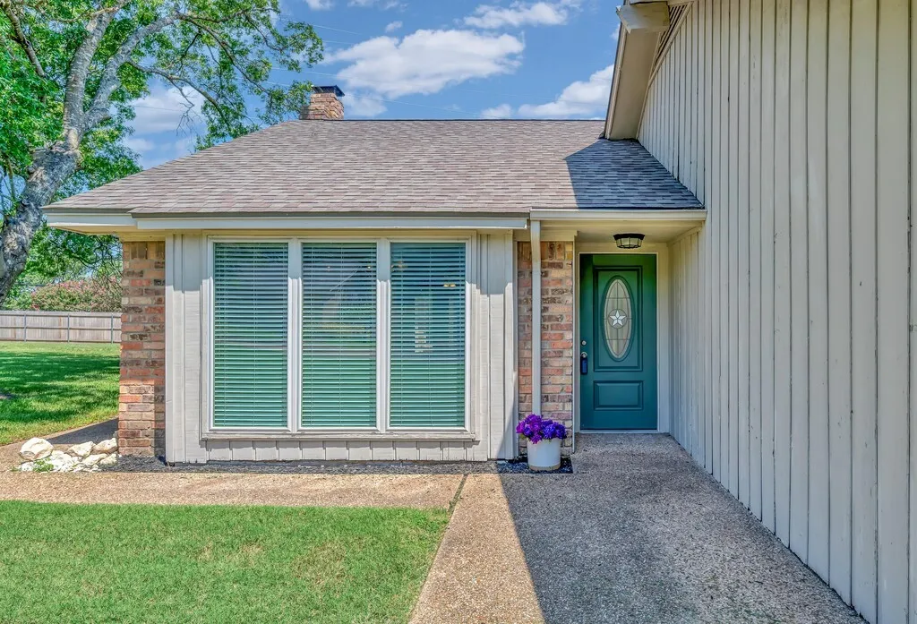 Brick and vertical siding exterior with a dark green entry door featuring an oval glass insert