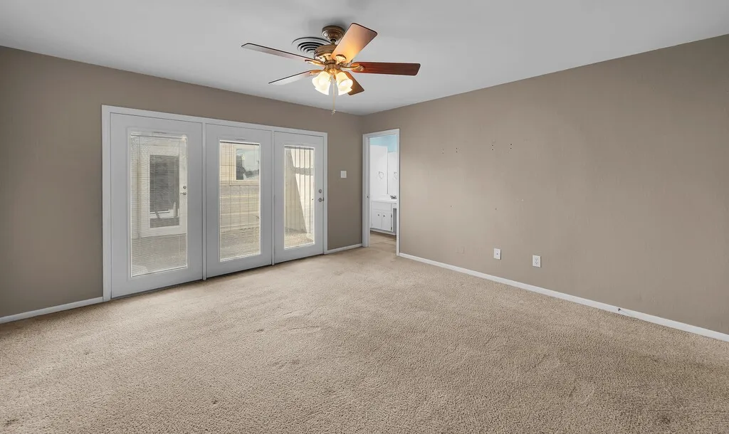 Spacious room with a ceiling fan, plush carpet, and light-colored walls