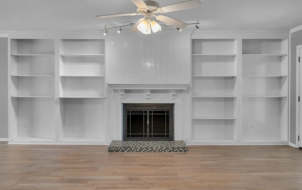 Central fireplace with a white mantel and beadboard surround, flanked by built-in shelving units