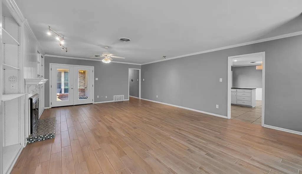 Spacious room featuring wood-finish flooring, a fireplace with a mosaic tile surround, and built-in shelving