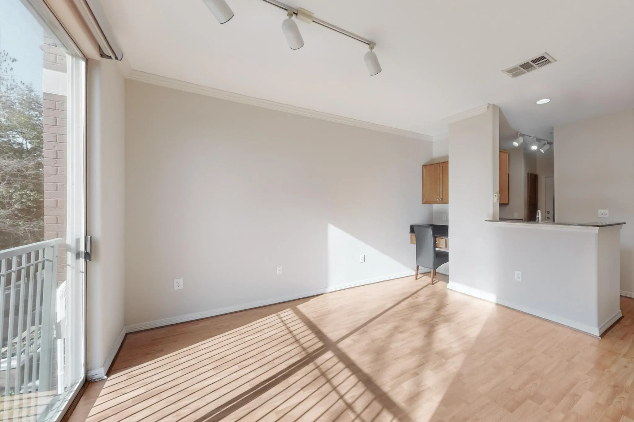 Empty room with light wood-type flooring, track lighting, and crown molding