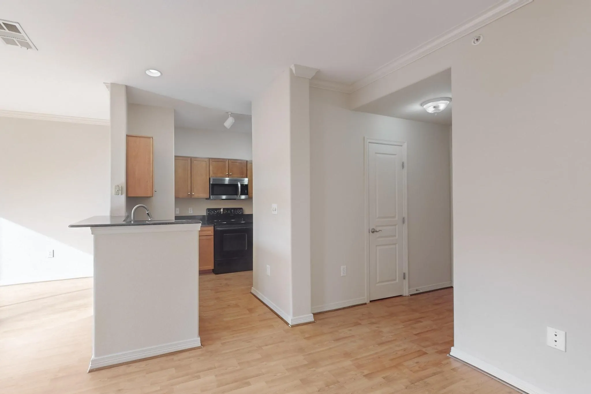 Kitchen featuring crown molding, electric range, light wood-type flooring, stainless steel microwave, and a peninsula