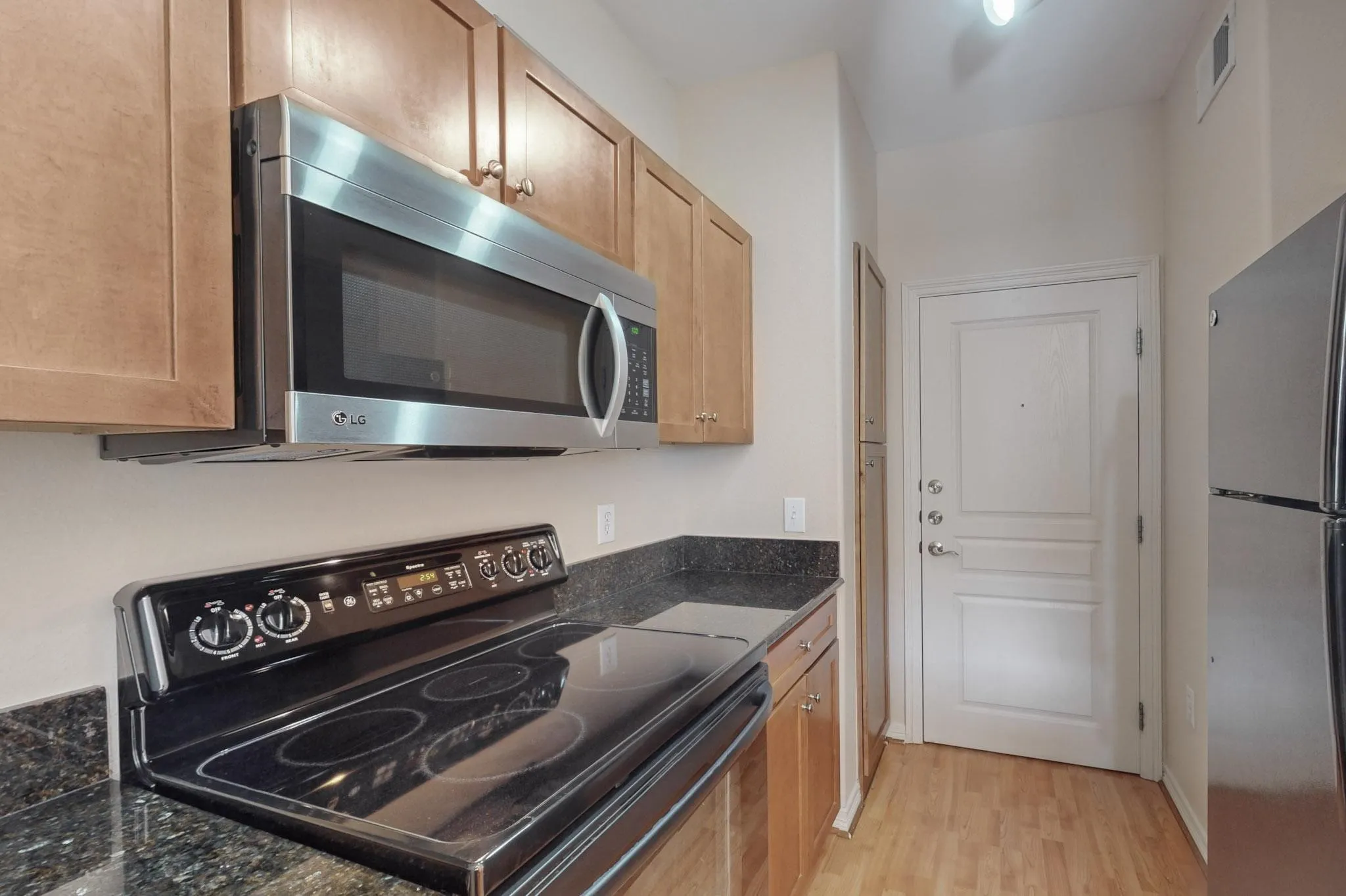 Kitchen featuring appliances with stainless steel finishes, dark stone countertops, and light wood finished floors