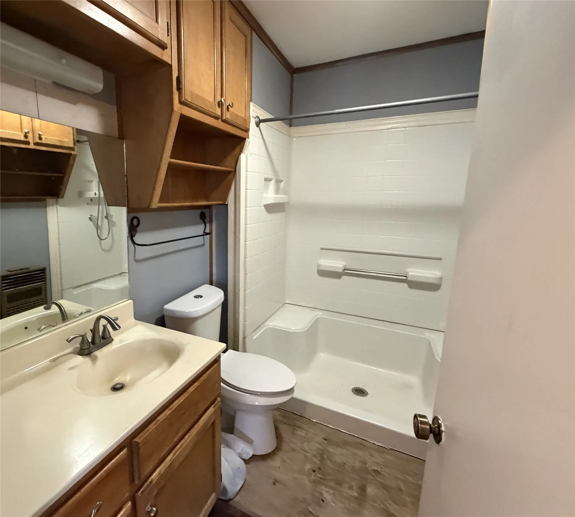 Bathroom featuring wood-finish flooring, a combination tub and shower unit, a vanity with integrated sink, wood cabinetry, and a mirrored wall