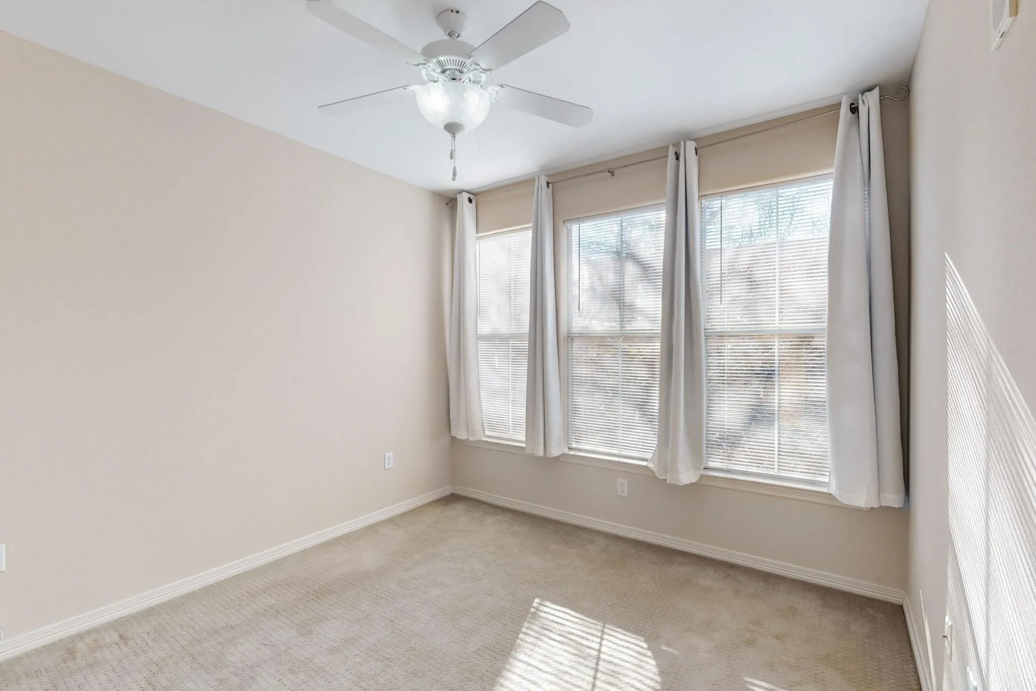 Carpeted spare room featuring baseboards and a ceiling fan