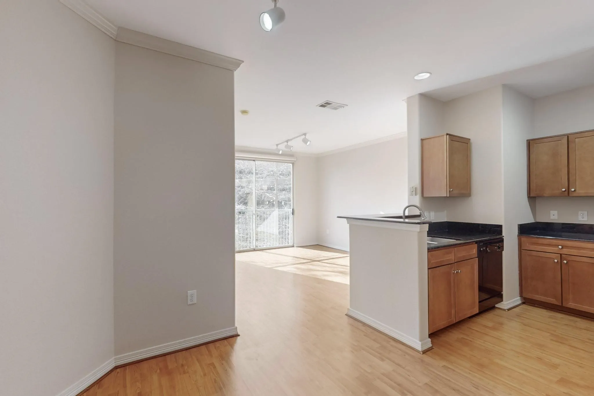 Kitchen with rail lighting, light wood-type flooring, dishwasher, brown cabinetry, and ornamental molding