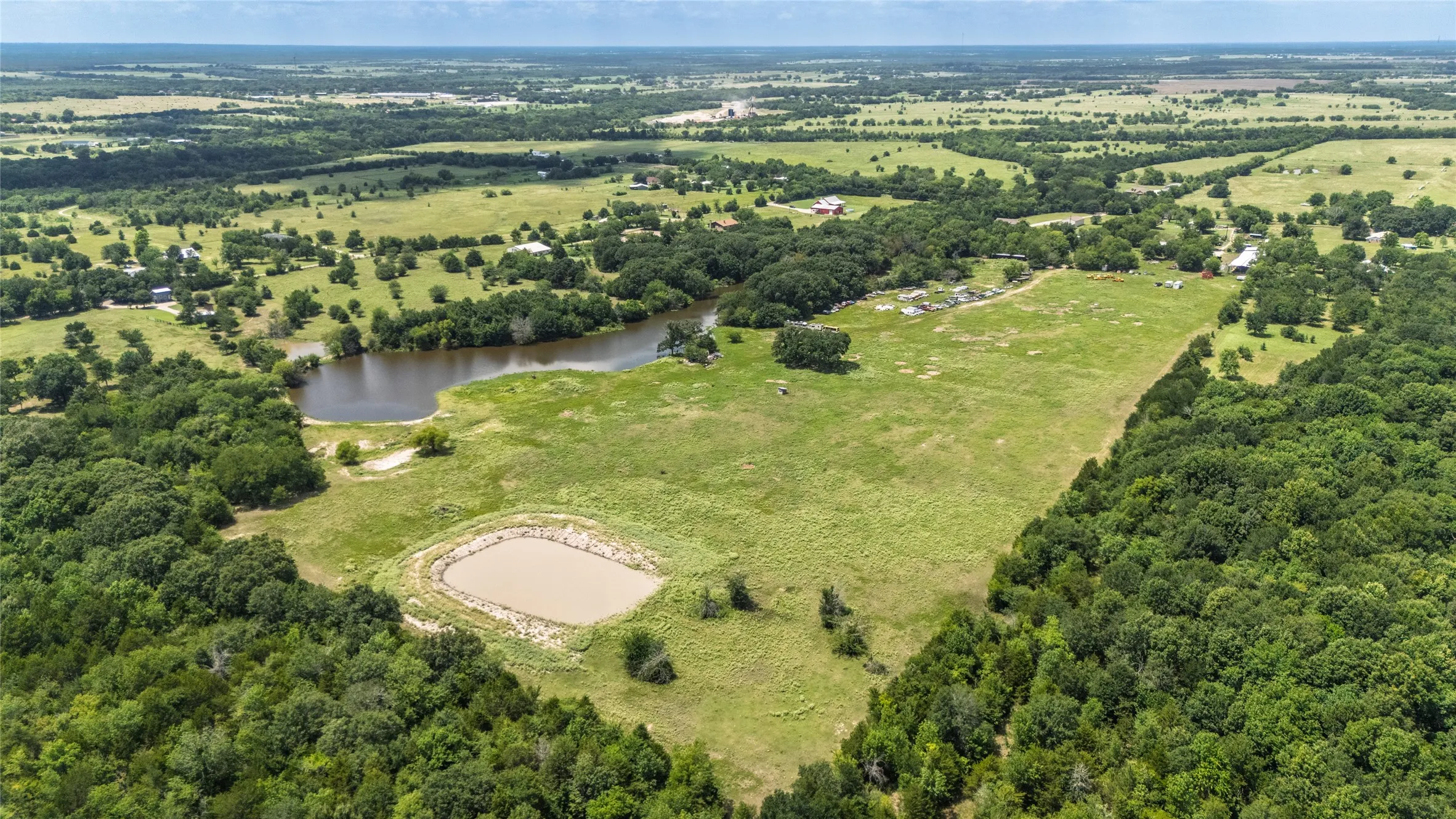Expansive rural landscape featuring a large pond and a smaller, contained body of water