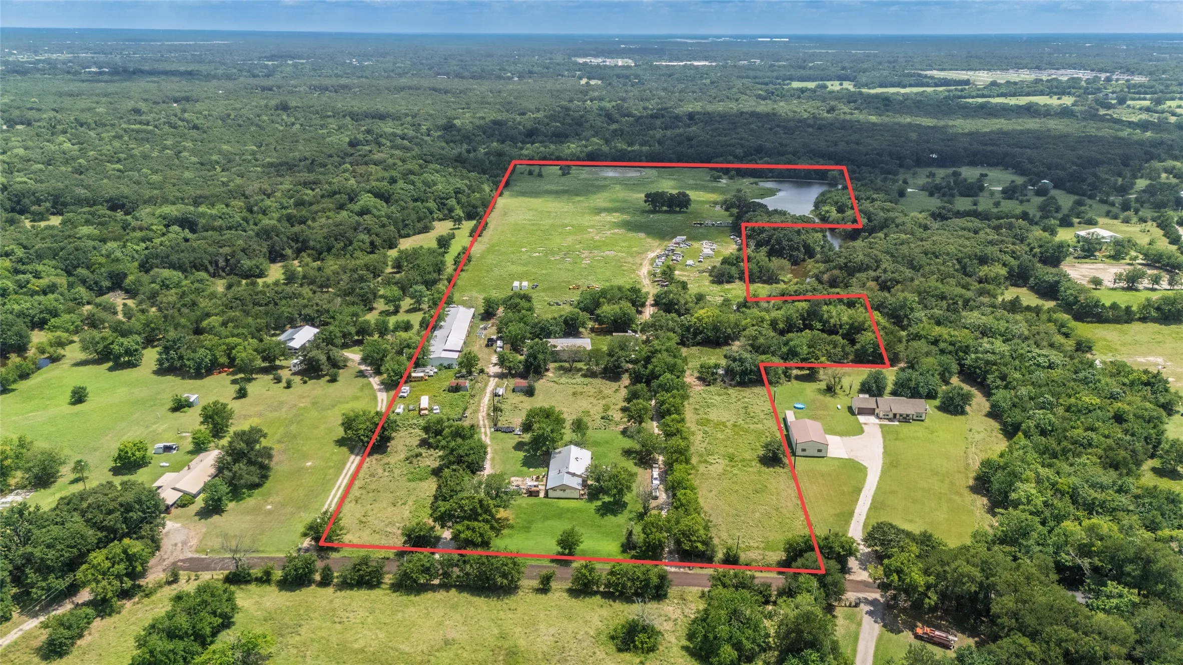 Expansive acreage featuring multiple structures, a private pond, and extensive wooded areas