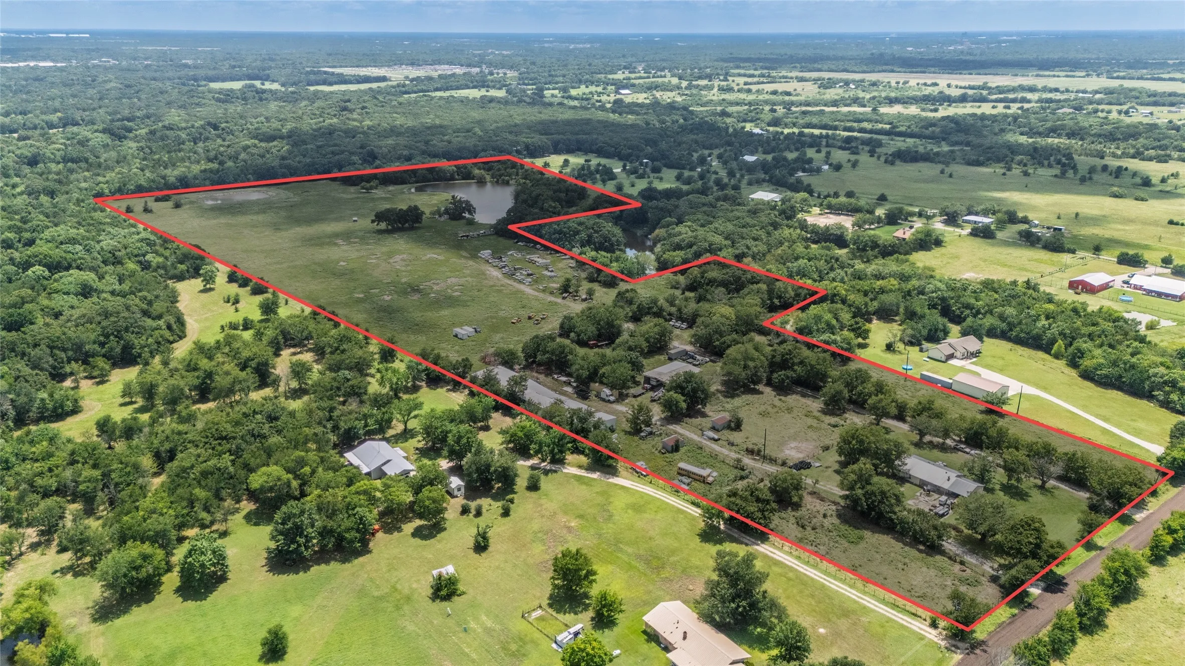 Expansive rural property featuring a large pond, extensive open fields, and multiple treed areas