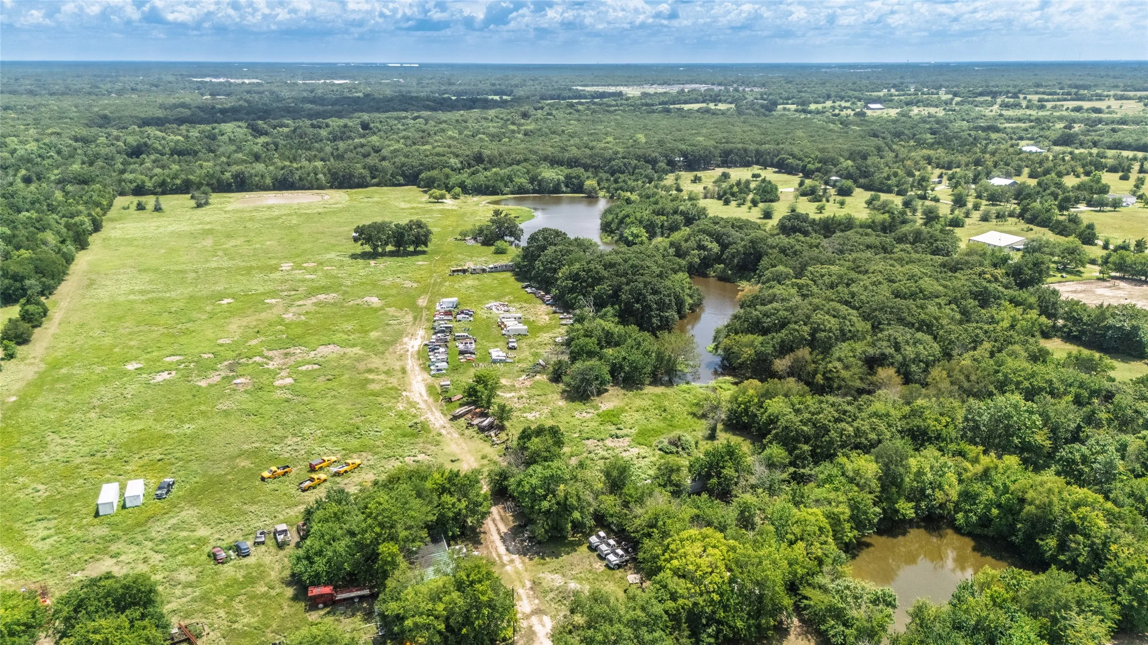 Expansive green acreage featuring a large pond and mature trees