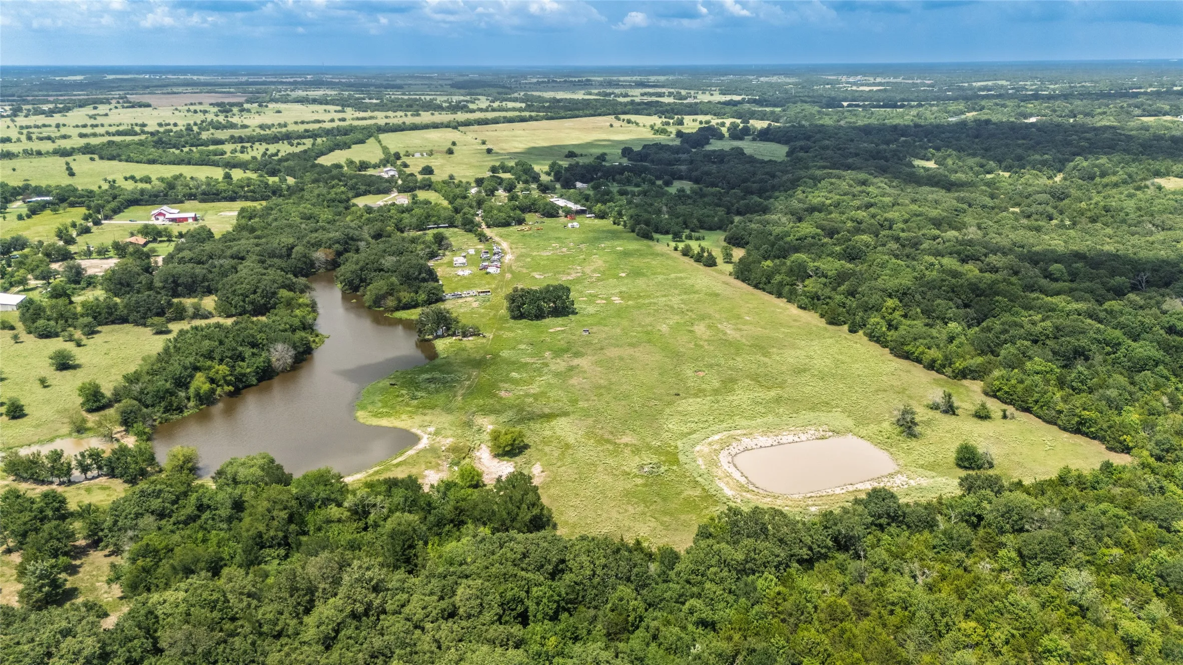Expansive rural property featuring a large natural pond, a secondary man-made pond, and extensive wooded areas