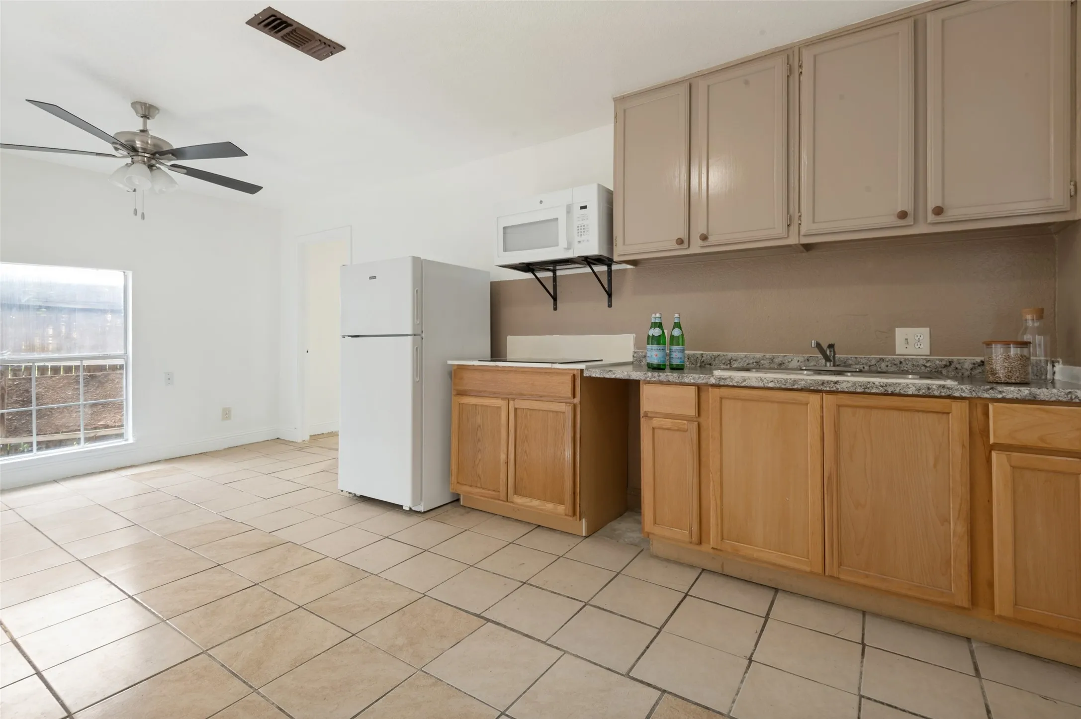 Kitchenette with tile flooring, light wood-finish base cabinetry, and contrasting upper cabinetry