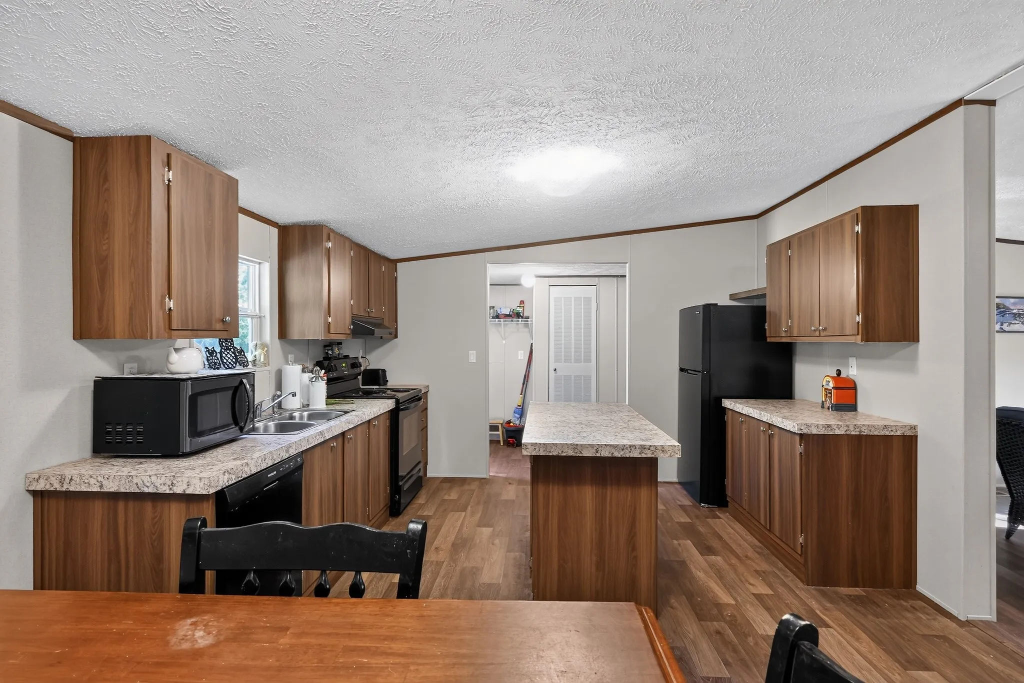 Kitchen featuring wood-finish cabinetry, speckled countertops, and wood-finish flooring