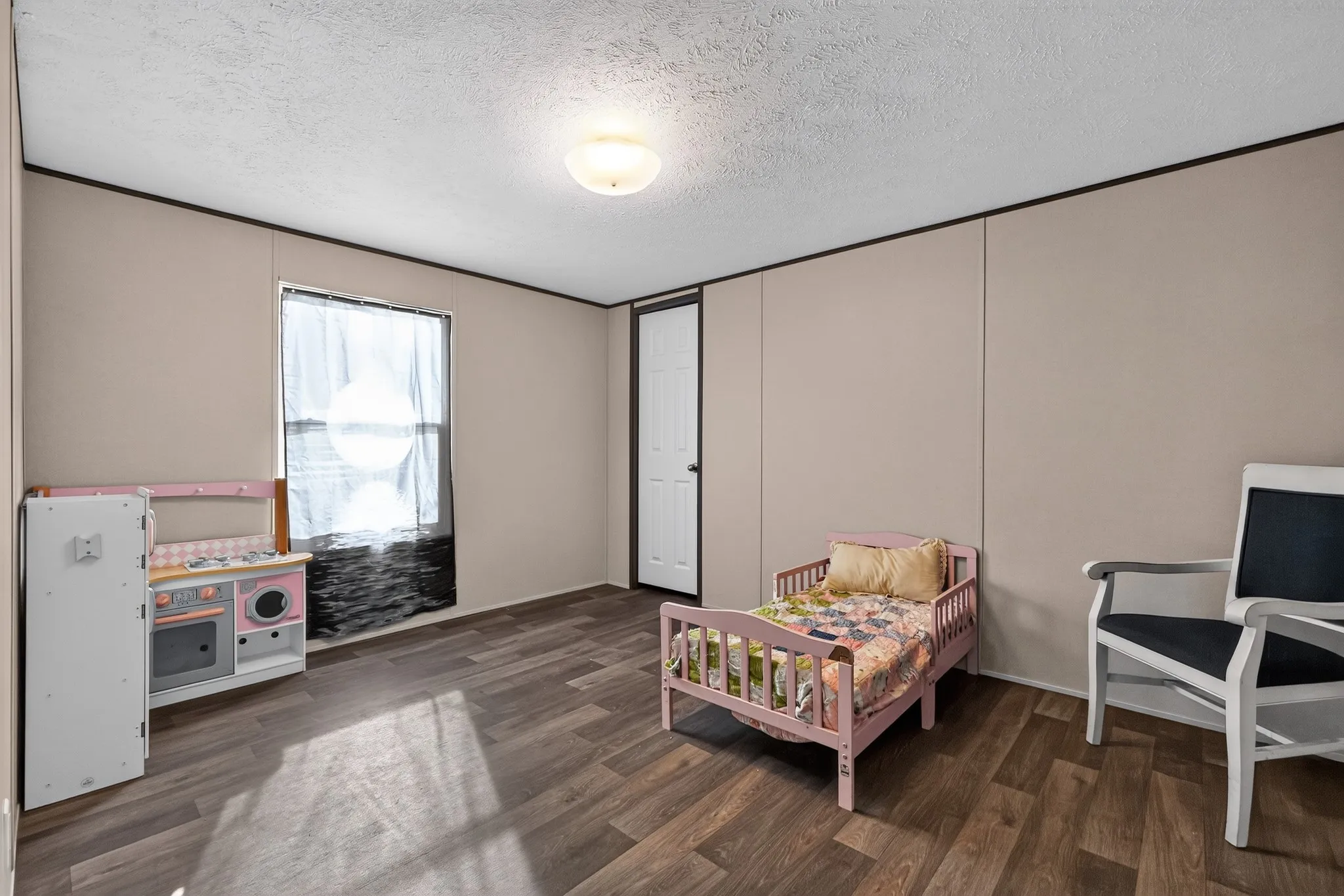 Room featuring wood-finish flooring, a single window with dark blinds, and neutral wall paneling