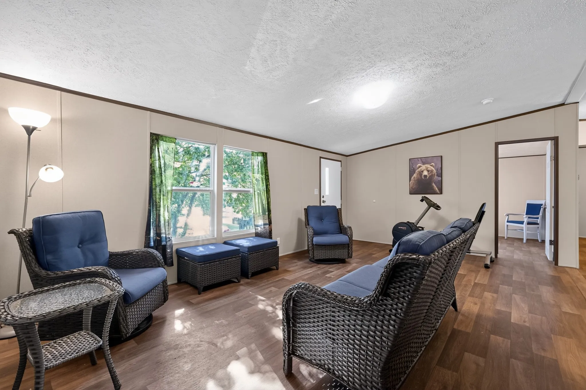 Living area featuring wood-finish flooring, neutral wall panels, and two double-pane windows